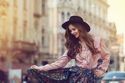brunette with long hair extensions wearing hat and dancing in the city