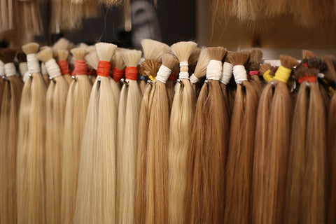 bundles of different colored blonde hair extensions hanging on the wall
