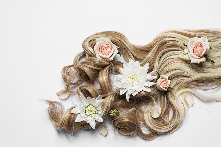 blonde hair extensions fanned out on a table with flowers