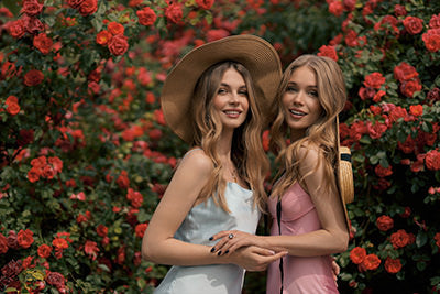 two women with long blonde hair extensions wearing in hats in roses