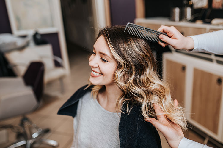 happy brunette woman in salon chair that just had blonde hair extensions added