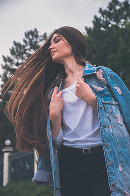 brunette with long hair extentions flipping hair in jean jacket