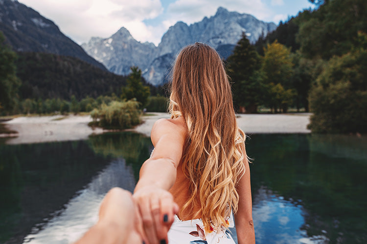 woman with hair extensions that give her blonde highlights in front of lake