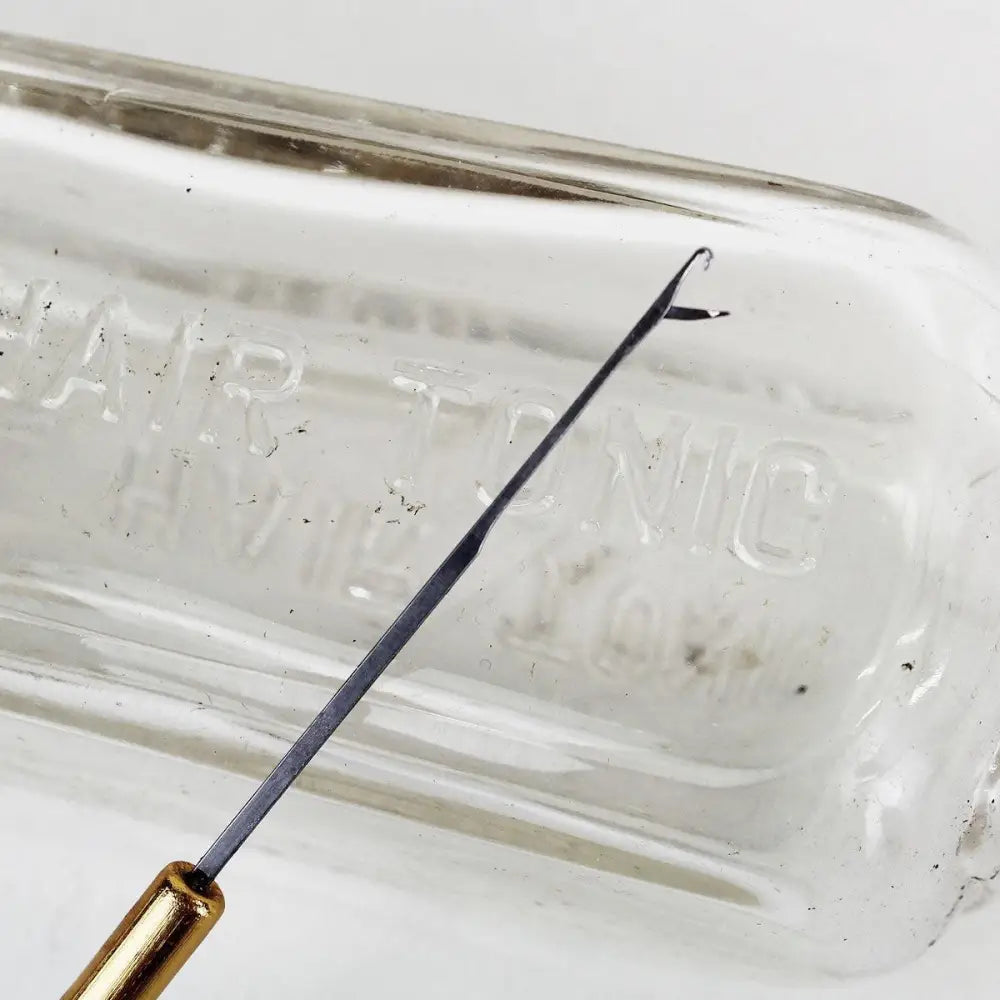 Metal top of latch hook microneedle leaning against glass bottle