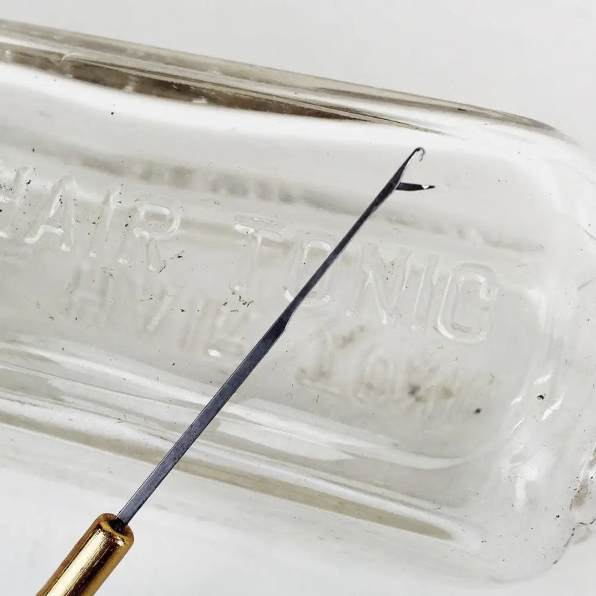 Metal top of latch hook microneedle leaning against glass bottle