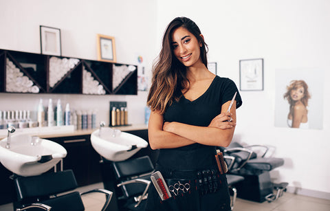 brunette female hair stylist in salon with sheers